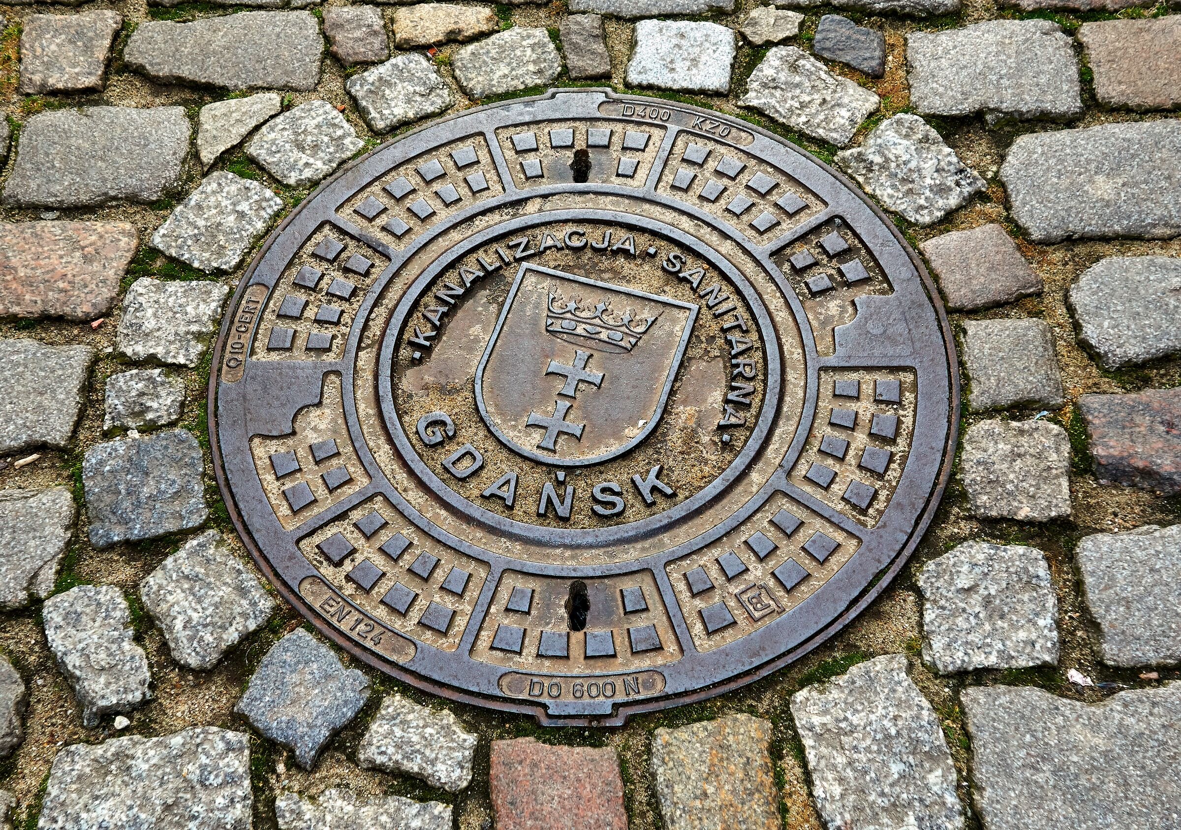 Rioolputdeksel in een straat met kasseien